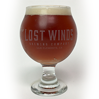 Riviera Rivi Rye is served in a chalice glass filled with a dark red ale with light foam from Lost Winds Brewing